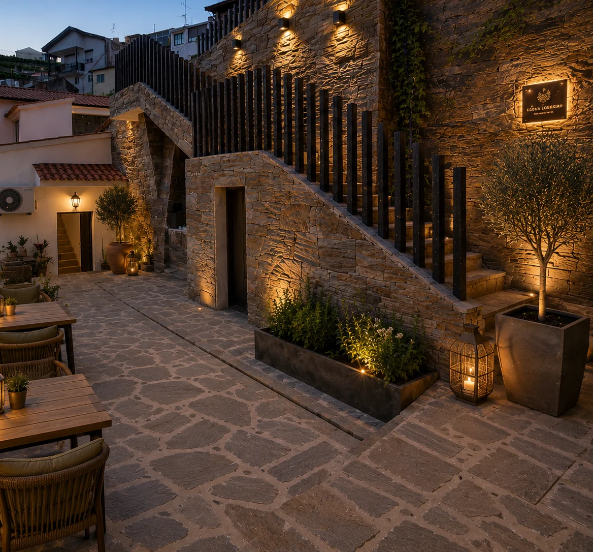 Pátio exterior em xisto com luz quente e recantos para estar.